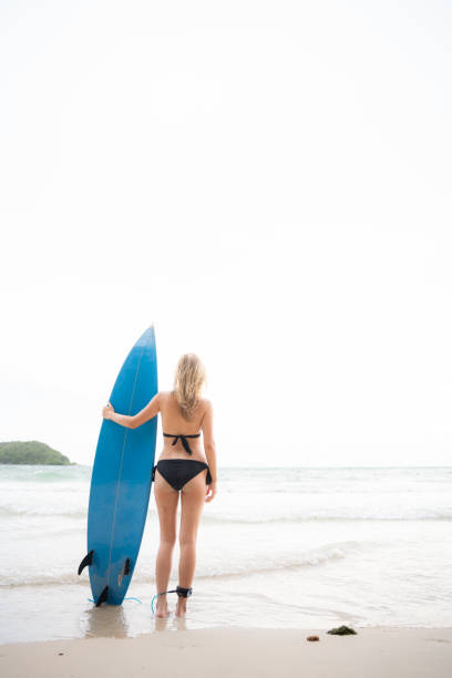 istock Surfer girl with her surfboard on the beach. 1635637044