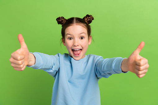 Photo of funny shocked cute small girl raise two hands thumb fingers up approve novelty quality isolated green color background.