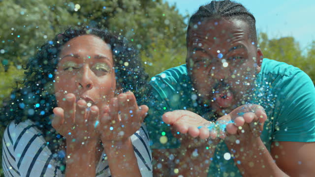 SLO MO LD Man and woman blowing glitter towards the camera lens