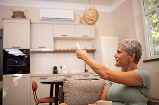 Woman turning on air conditioner with remote