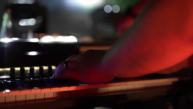 Hands of male musician playing at synthesizer