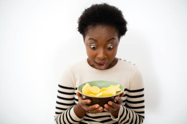 istock young back woman with bowl of chips and surprised expression 1635691151