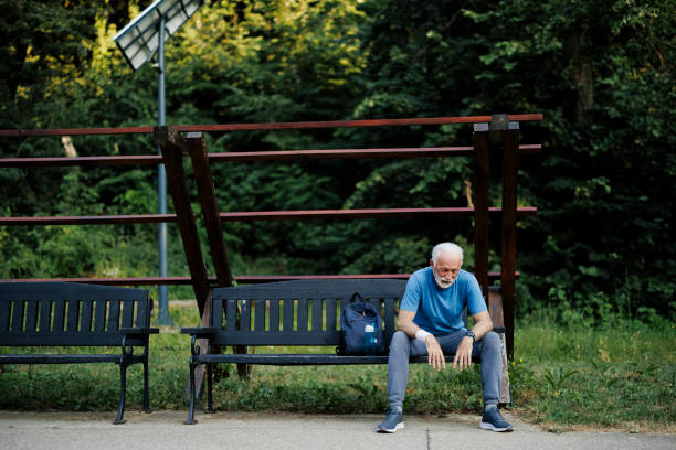 Tired senior sporty man resting on park bench