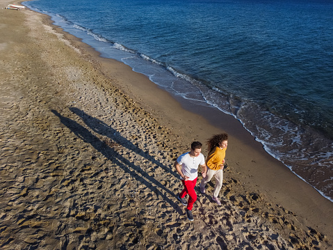 Beautiful young couple running on the beach in Nea Flogita, Greece. Taken with drone.