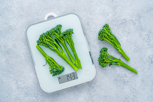 Healthy eating and dieting: fresh broccoli on kitchen scale. High resolution 42Mp studio digital capture taken with SONY A7rII and Zeiss Batis 40mm F2.0 CF lens