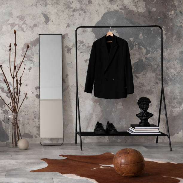istock The stylish compostion at living room interior with design gray sofa, bench, coffee table, hanger, lamp and elegant personal accessories. Loft and industrial interior. Mock up poster. Template. 1635735418
