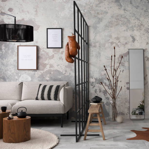 istock Exquisite and modern composition of living room interior with design grey sofa, bench, plant, brown coffee tables, decoration, pillow and elegant accessories. Concrete grunge wall. Template. 1635735977