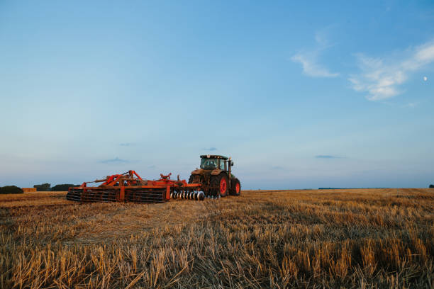 istock Modern tractor with a heavy trailed disc harrow works a wide hilly field. Autumn or spring agricultural campaign 1635748947
