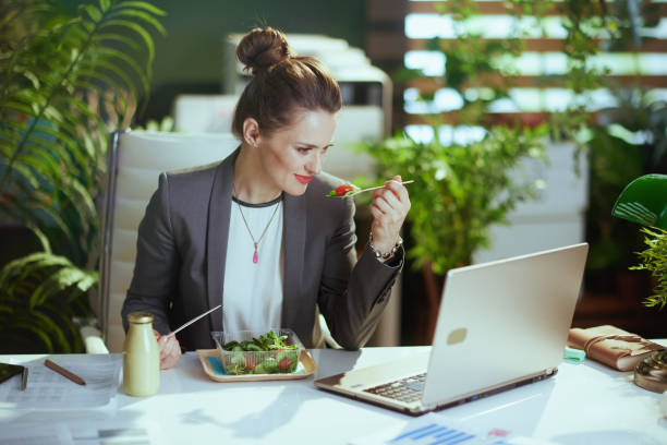 istock modern accountant woman in modern green office eating salad 1635772482