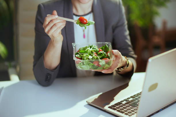 istock Modern woman worker in green office eating salad 1635772486