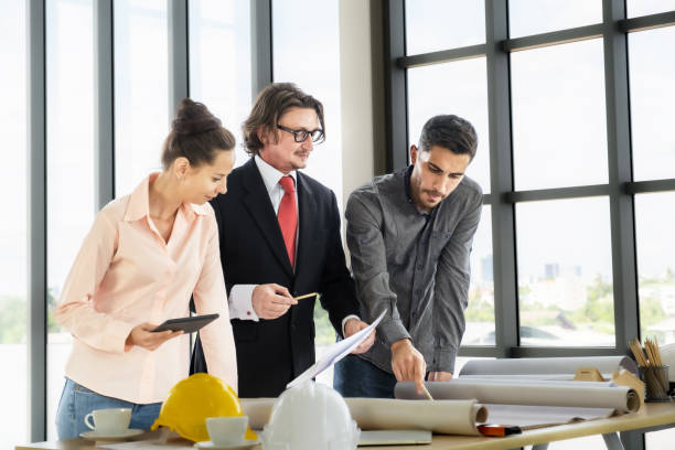 istock Engineer team meeting to inspect the construction blueprint drawings, work plan and distribute work before starting the building 1635772502