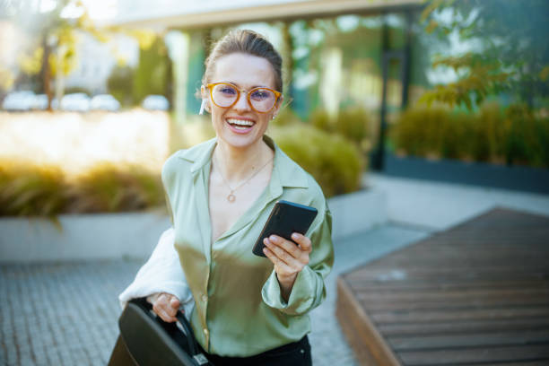 istock female worker in green blouse using phone and walking 1635778065