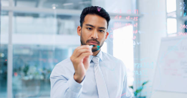 istock Thinking, strategy and serious businessman writing on glass wall with thoughtful analysis in office. Brainstorming, planning and vision of corporate worker with focus, concentration and idea. 1635786119