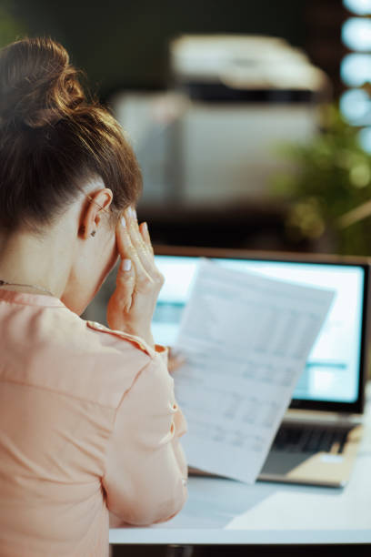 istock Seen from behind modern woman with documents having headache 1635794881