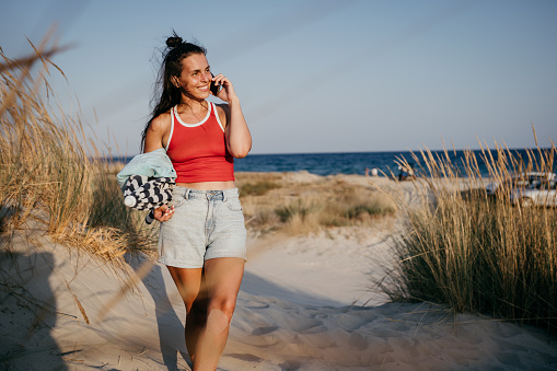 Young beautiful woman using mobile phone at the beach