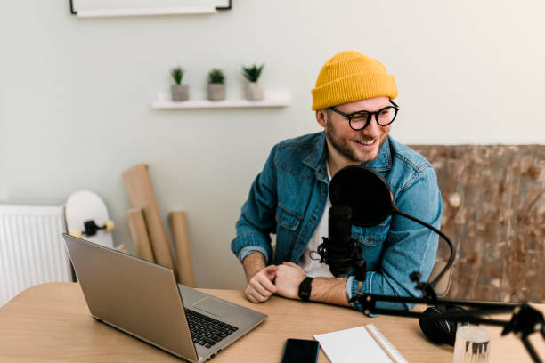 istock Young smiling man recording podcast and doing live streaming using microphone and headphones in recording studio 1635801084