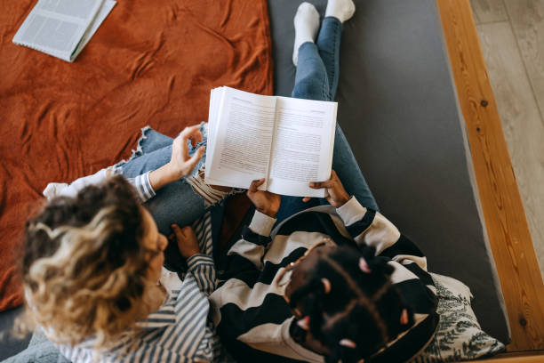 istock High angle view of two female students studying while sitting on a bed in a bedroom 1635802267