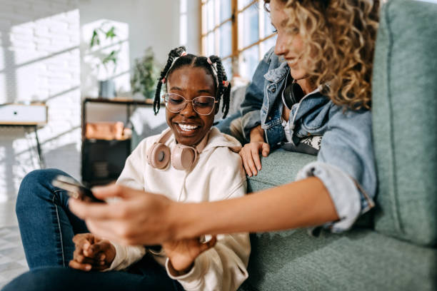 istock Two young smiling female roommates using phone together at home 1635804533
