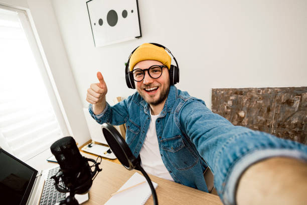 istock Self portrait of Young smiling man recording podcast and doing live streaming using microphone and headphones in recording studio 1635806765