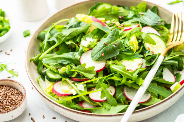 istock Green salad with spinach, arugula and radish with olive oil. 1635807333