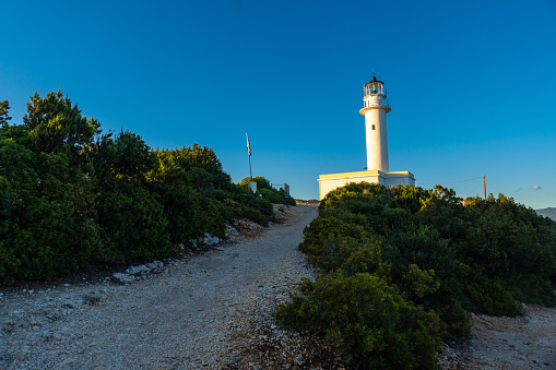Trail to the white lighthouse or Cape Ducato Lefkas at sunset in the southern area of the island of Lefkada. Greece.