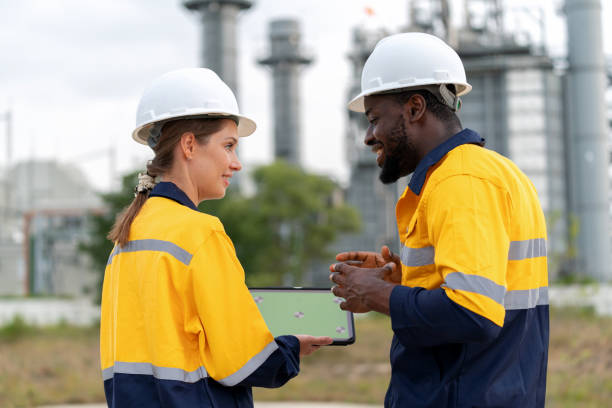 istock Mechanical engineers engrossed in discussions over a digital tablet with a green screen against the backdrop of the electric power plant. Essence of Technology, Communication, and Collective Expertise. 1635825754