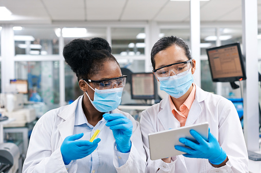 Female medical researchers discussing over tablet PC while working in laboratory