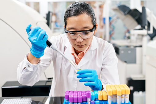 Female scientist doing research wearing protective eyeglasses while working in laboratory
