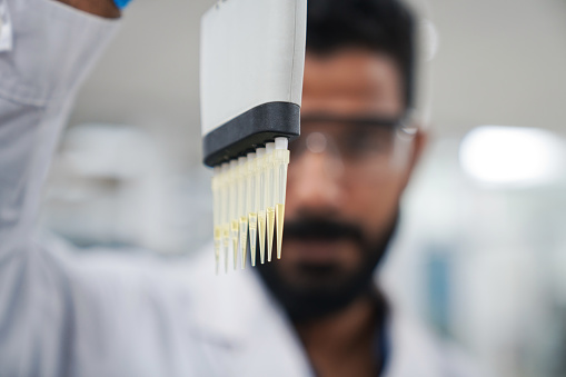 Nozzles of pipette with medical sample held by scientist in laboratory