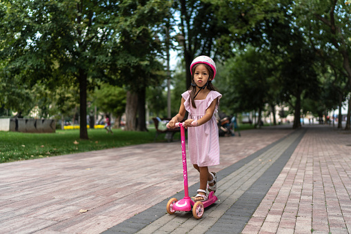 Little girl riding a push scooter