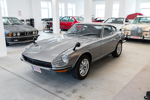 Vilnius, Lithuania - April 11, 2023: A rare JDM Datsun Fairlady Z parked in a private showroom, surrounded by other vintage cars in collection. Car after full restoration, painted in elegant grey colour.