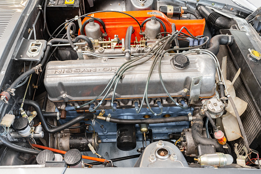 Vilnius, Lithuania - April 11, 2023: A rare JDM Datsun Fairlady Z parked in a private showroom, surrounded by other vintage cars in collection. Car after full restoration, painted in elegant grey colour. Engine bay view. 2.8 liter inline 6 engine.