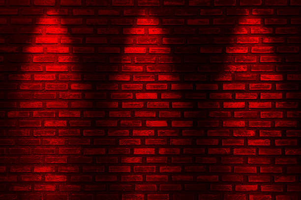 Red neon bulbs on red brick wall. Background texture of empty red wall with red neon light lamp style glow.