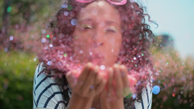 SLO MO Woman blowing glitter off her hands into the camera