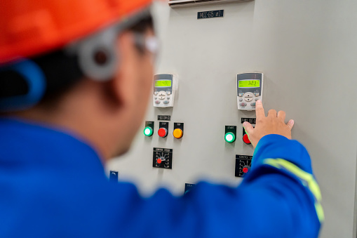 Technician worker in safety uniform monitor and inspect the temperature of electric cabinet at a switchgear box within a manufacturer's environment. Engineer unwavering commitment to ensuring the continuous operation of Electrical Systems.