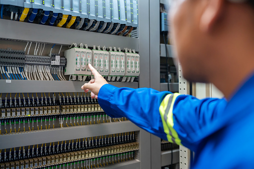Close up hand of Electrical engineer inspecting a circuit breaker at the switchgear room in a factory to maintain power supply and preventing disruptions. Ensures the continued smooth operation of Industrial Equipment. Amidst the controlled environment.