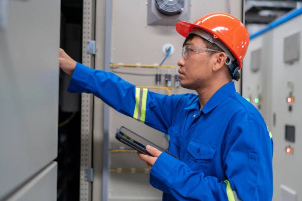 istock Electric engineer opens an electric cabinet for preventive maintenance within factory. Essence of Technology, Industry, and Proactive Care. The engineer's role in System Configuration and Distribution Board management. Safety remains in the factory. 1635932305
