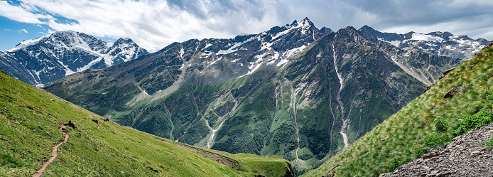 Snowy peaks of the Caucasus Mountains against a background of blue sky and white clouds