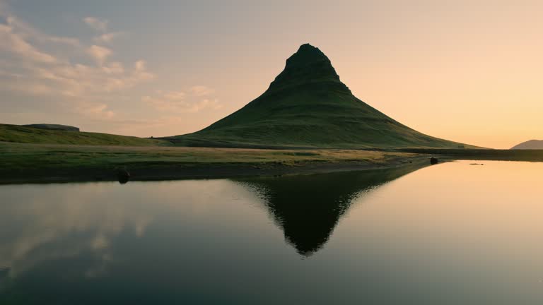 Golden sunrise over Kirkjufell mountain with lake reflection in summer at Iceland