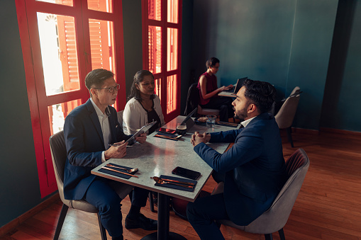 Senior and diverse managers interview a male applicant at a job hiring process in a restaurant setting