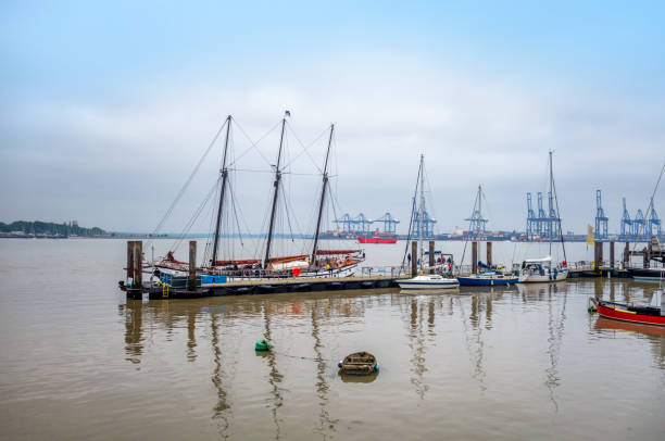 A three-masted gaff schooner, ‘Trinovante’, moored in Harwich Harbour, Essex. ‘Trinovante’ carries guests who are interested in sailing ships under expert instruction. She was constructed in the early 1980s at Wivenhoe in Essex and is named after one of the ancient tribes of East Anglia who occupied that region. In the background are some of the cranes at Port of Felixstowe in Suffolk, the UK’s largest container port.