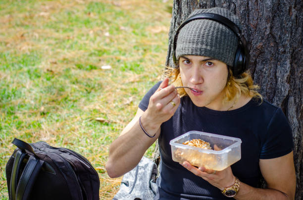young man eating lunch outside in the park