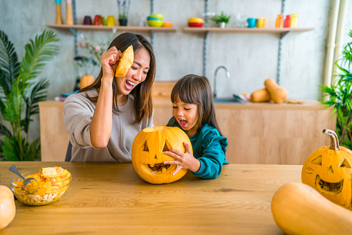 Happy mother and daughter making Halloween decorations at home