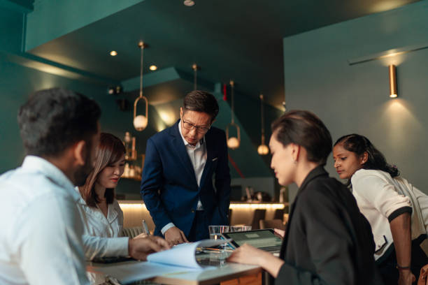 Diverse white collar professionals discusses work during business lunch stock photo