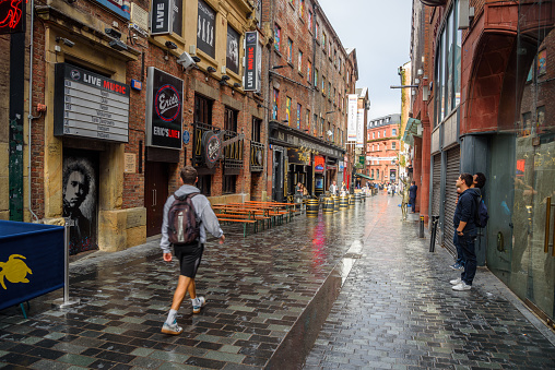 Liverpool, UK - July 11, 2023: People in Mathew Street after a summer thunderstorm. Mathew Street, one of the most popular nightlife destinations in central Liverpool, is famous because it houses Cavern Club  frequented by The Beatles before they became famous worldwide. Historically the street was the centre of Liverpool's wholesale fruit and vegetable market.