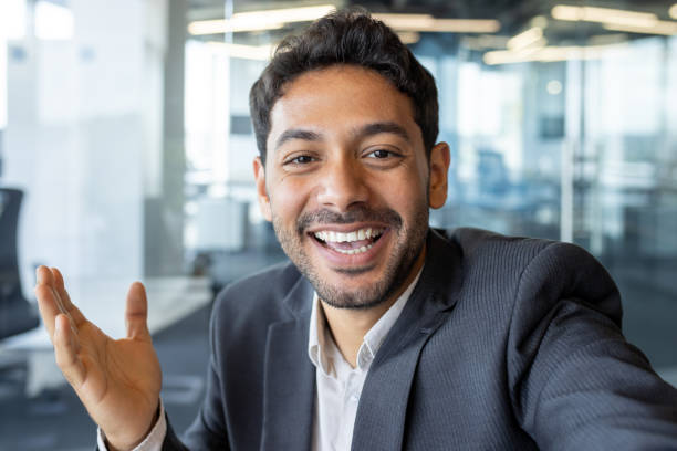 istock Video call friendly conversation, arab businessman inside office talking with friends and colleagues at workplace, man using app on phone, smiling and friendly waving at camera 1636023296