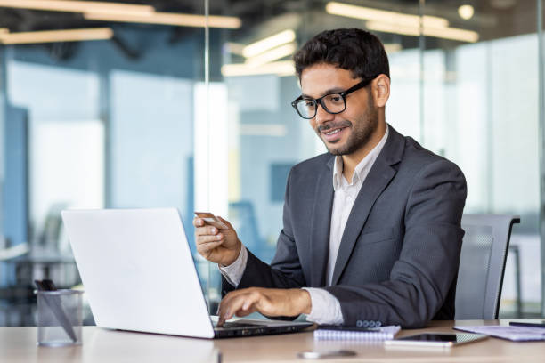 istock Happy successful businessman with bank credit card inside office at workplace, man using laptop for online shopping and money transfer 1636024438