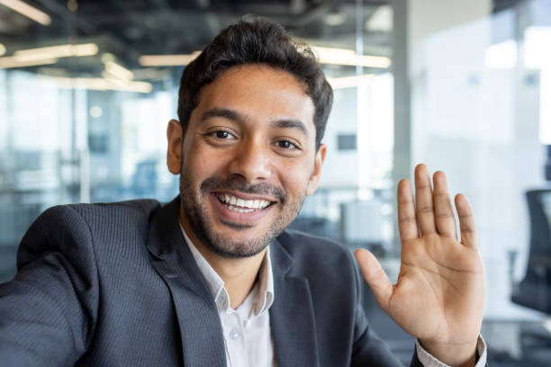 istock Video call friendly conversation, arab businessman inside office talking with friends and colleagues at workplace, man using app on phone, smiling and friendly waving at camera 1636025014
