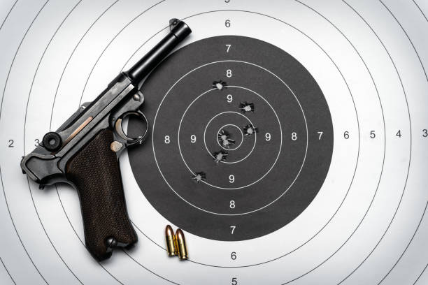 istock Retro style pistol and  paper target with bullet holes 1636054338