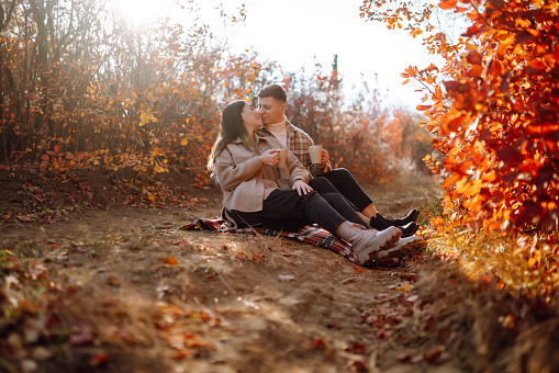 Couple in love rests and walks together in the autumn park. Stylish man and woman enjoy autumn weather. Concept of love, relationships, relaxation.